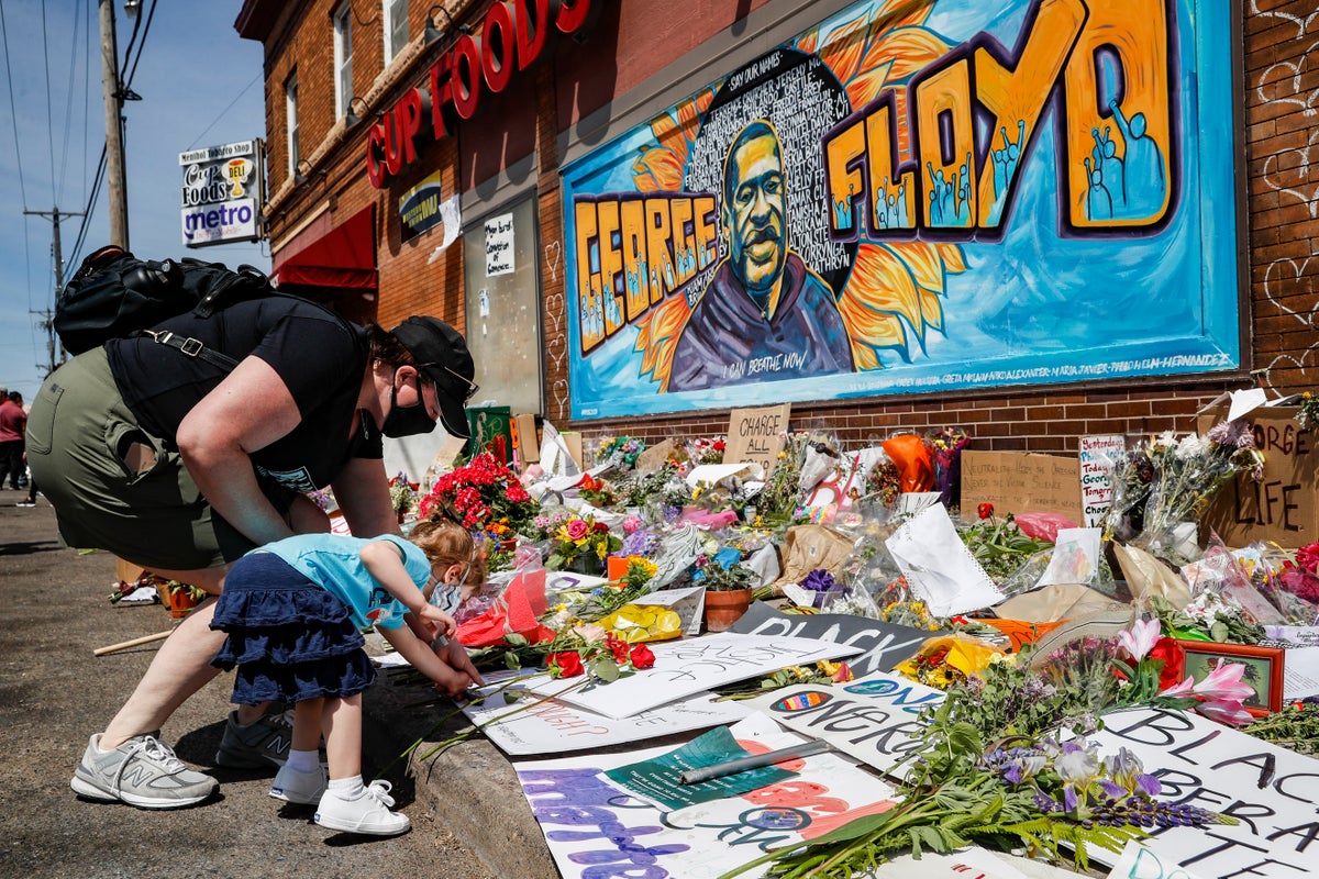 Jessica Knutson, and her daughter Abigail, 3, place flowers at a memorial to George Floyd, Sunday, May 31, 2020, in Minneapolis. Protests continued following the death of Floyd, who died after being restrained by Minneapolis police officers on May 25. (AP Photo/John Minchillo)