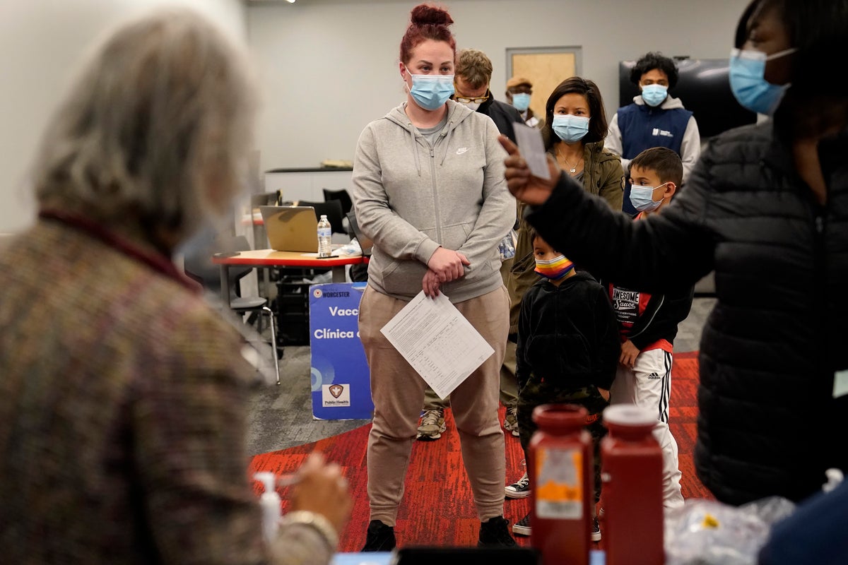 Leah Perkins, of Worcester, Mass., center, stands in line to receive a booster shot of the Pfizer COVID-19 vaccine, Dec. 2, 2021, at a mobile vaccination clinic, in Worcester. More U.S. states desperate to defend against COVID-19 are calling on the National Guard and other military personnel to assist virus-weary medical staffs at hospitals and other care centers. (AP Photo/Steven Senne, File)
