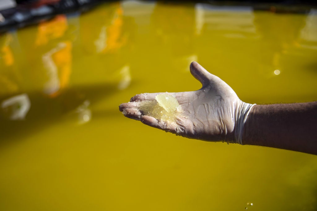 A visitor holds lithium concentrate for a photograph at a Sociedad Química y Minera de Chile (SQM) lithium mine on the Atacama salt flat in the Atacama Desert, Chile, on Wednesday, May 29, 2019. Almost three-quarters of the world's lithium raw materials come from mines in Australia or briny lakes in Chile, giving them leverage with customers scrambling to tie up supplies. The mining nations hope to bring refining and manufacturing plants that could help kickstart domestic technology industries. Photographer: Cristobal Olivares/Bloomberg via Getty Images