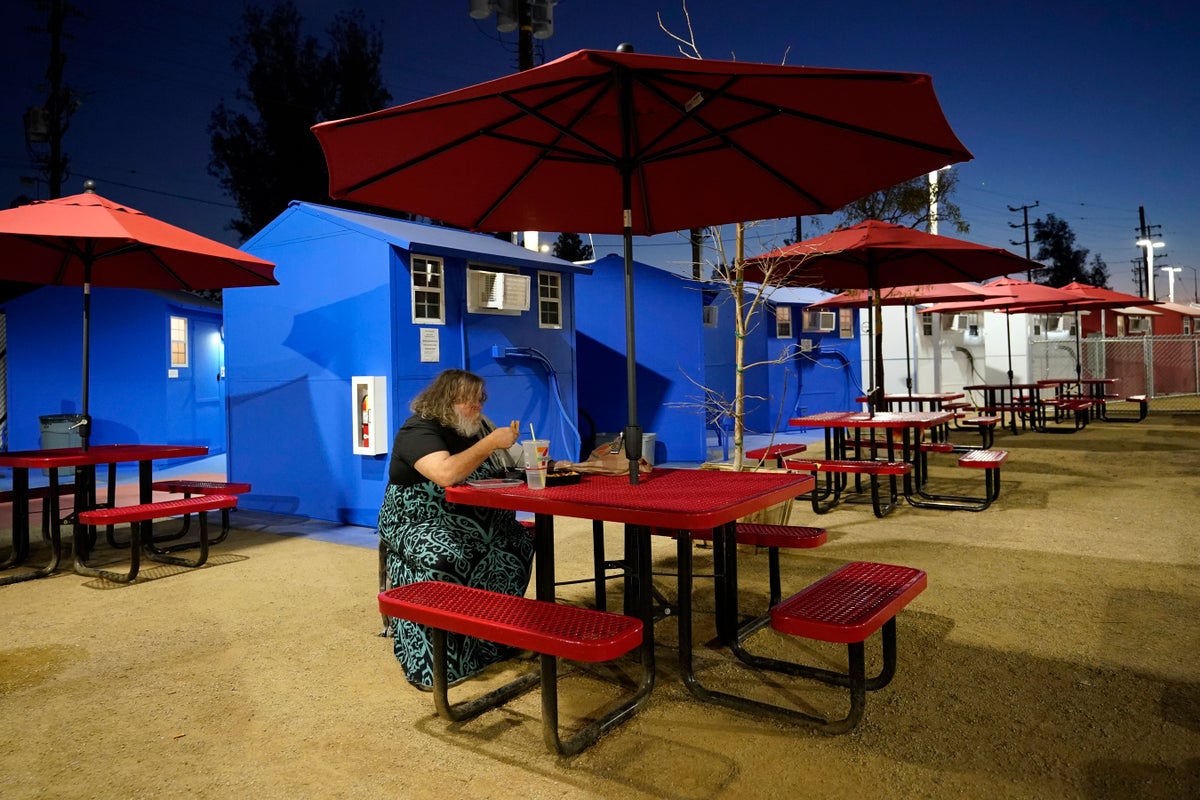 A resident eats in front of a row of tiny homes for the homeless, Thursday, Feb. 25, 2021, in the North Hollywood section of Los Angeles. (AP Photo/Marcio Jose Sanchez)