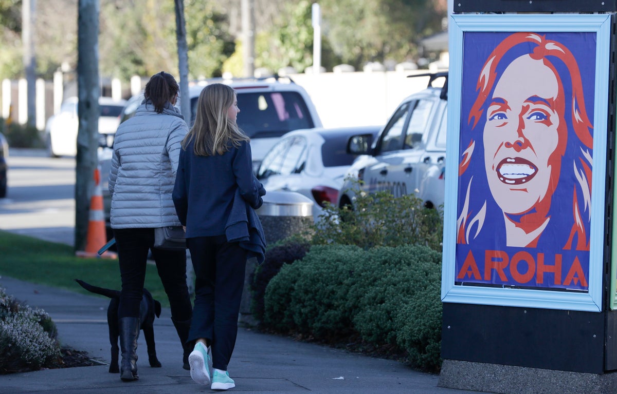 Pedestrians walk past a billboard featuring Prime Minister Jacinda Ardern with the word Aroha, meaning love, in Christchurch, New Zealand, Monday, June 8, 2020. New Zealand appears to have completely eradicated the coronavirus, at least for now, after health officials said Monday the last known infected person had recovered. (AP Photo/Mark Baker)