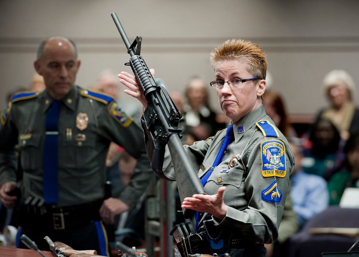 Firearms training unit Detective Barbara J. Mattson, of the Connecticut State Police, holds up a Bushmaster AR-15 rifle, the same make and model of gun used by Adam Lanza in the Sandy Hook School shooting. (AP Photo/Jessica Hill)