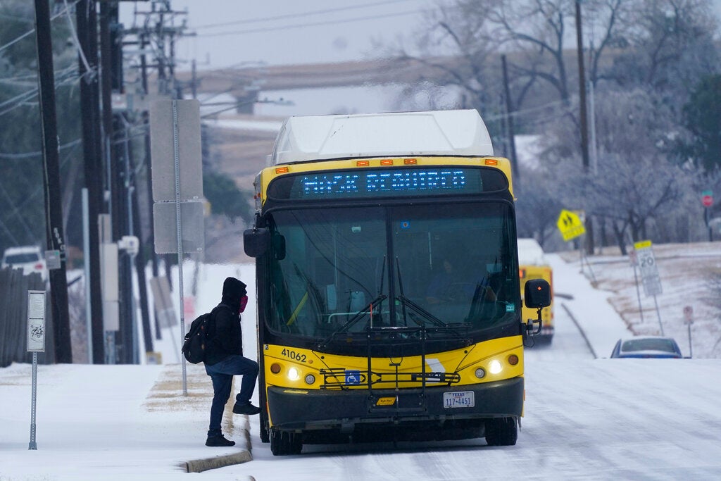 A rider steps onto a bus during a light freezing rain in Dallas, Thursday, Feb. 3, 2022. A major winter storm with millions of Americans in its path is spreading rain, freezing rain and heavy snow further across the country. (AP Photo/LM Otero)
