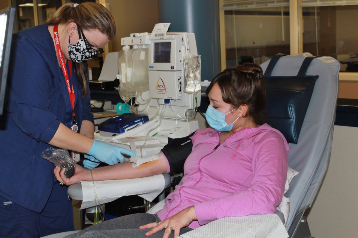 In this April 22, 2020 photo provided by New York Blood Center Enterprises, Aubrie Cresswell, 24, donates convalescent plasma at the Blood Bank of Delmarva Christiana Donor Center in suburban Newark, Del. (New York Blood Center Enterprises via AP)