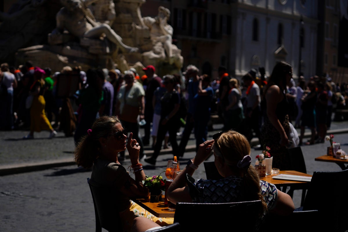 Tourists sit at a bar in Piazza Navona in downtown Rome, Wednesday, April 27, 2022. (AP Photo/Gregorio Borgia)