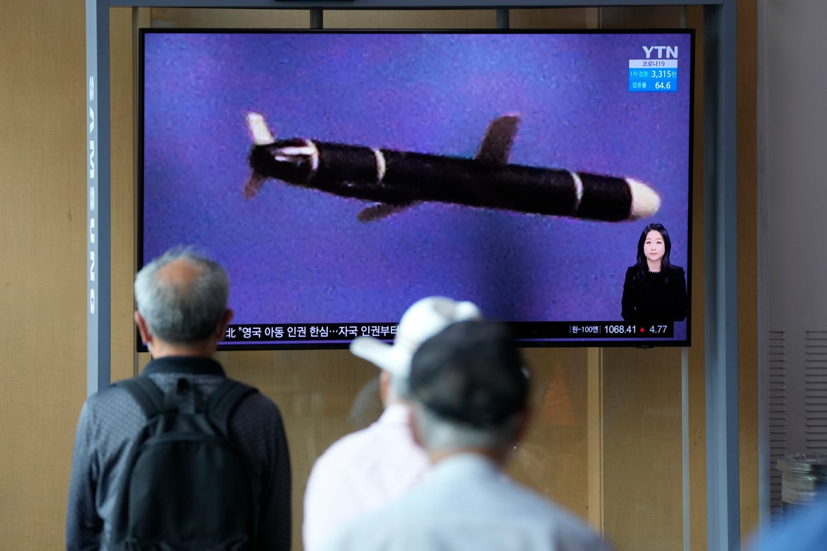 People watch a TV screen showing a news program showing a North Korean handout photo that says, 