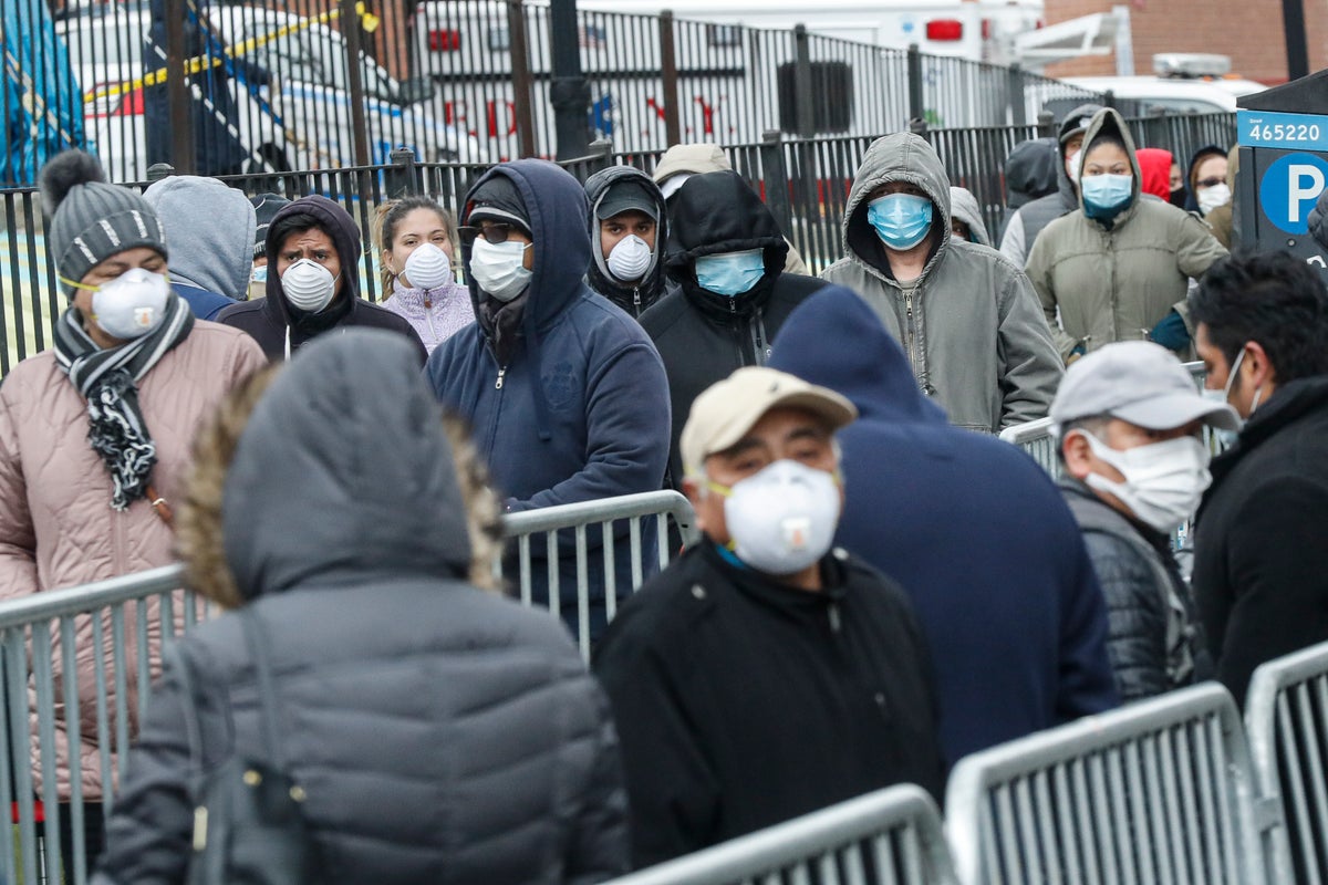Patients wear personal protective equipment while maintaining social distancing as they wait in line for a COVID-19 test at Elmhurst Hospital Center, Wednesday, March 25, 2020, in New York. (AP Photo/John Minchillo)