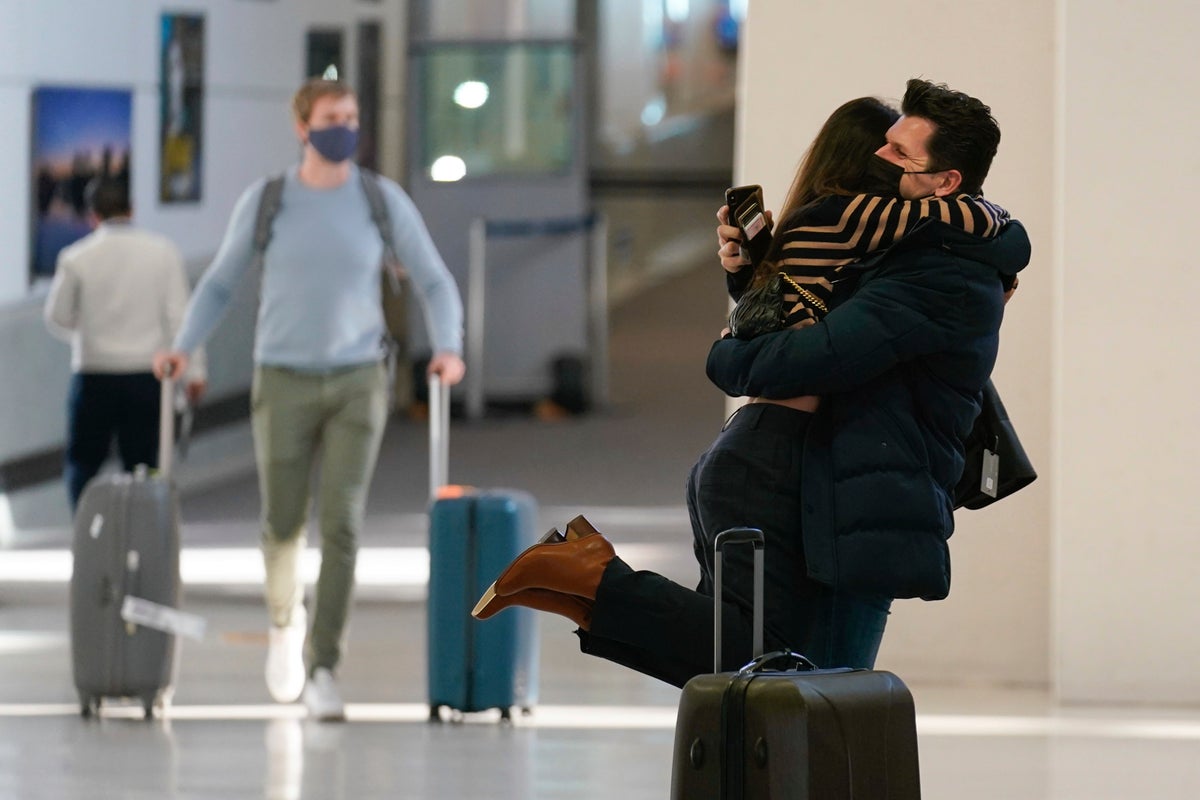 Natalia Abrahao is lifted up by her fiancé Mark Ogertsehnig as they greet one another at Newark Liberty International Airport in Newark, N.J., Monday, Nov. 8, 2021. Pandemic travel restrictions have made their recent meetings difficult and infrequent. The U.S. lifted restrictions Monday on travel from a long list of countries including Mexico, Canada and most of Europe, setting the stage for emotional reunions nearly two years in the making and providing a boost for the airline and tourism industries decimated by the pandemic. (AP Photo/Seth Wenig)
