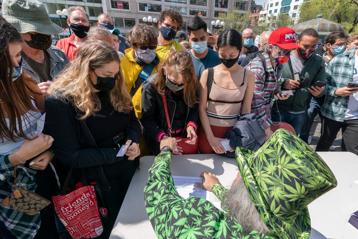 A man wearing a cannabis costume hands out marijuana cigarettes during a 
