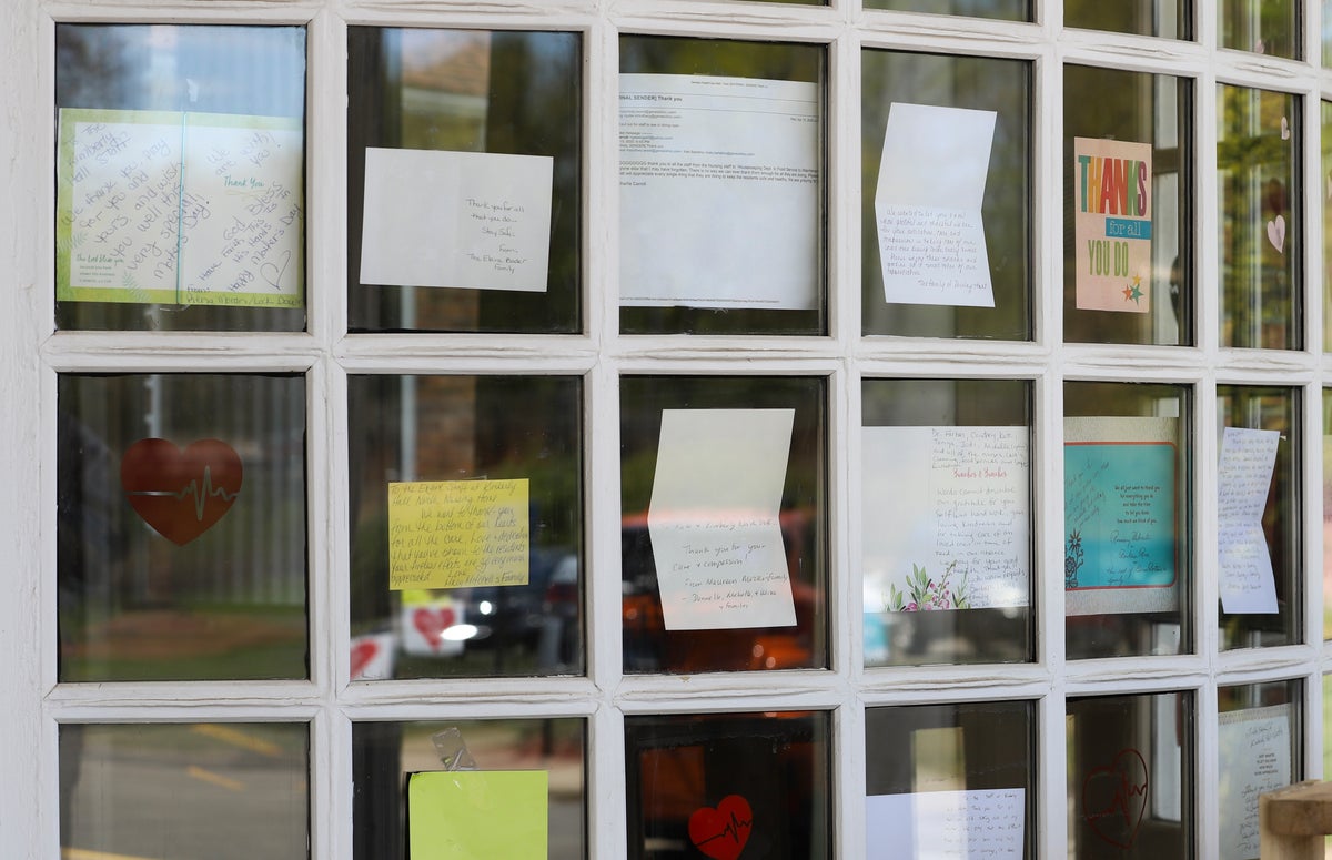 Notes for healthcare workers hang in the front window at the Kimberly Hall North nursing home, Thursday, May 14, 2020 in Windsor, Conn. Preliminary research indicates the numbers of nursing home residents testing positive for the coronavirus and dying from COVID-19 are linked to location and population density — not care quality ratings. (AP Photo/Chris Ehrmann)